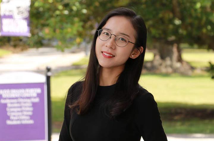 Staff member Helena Xia smiles for the camera outside Olive Swann Building.