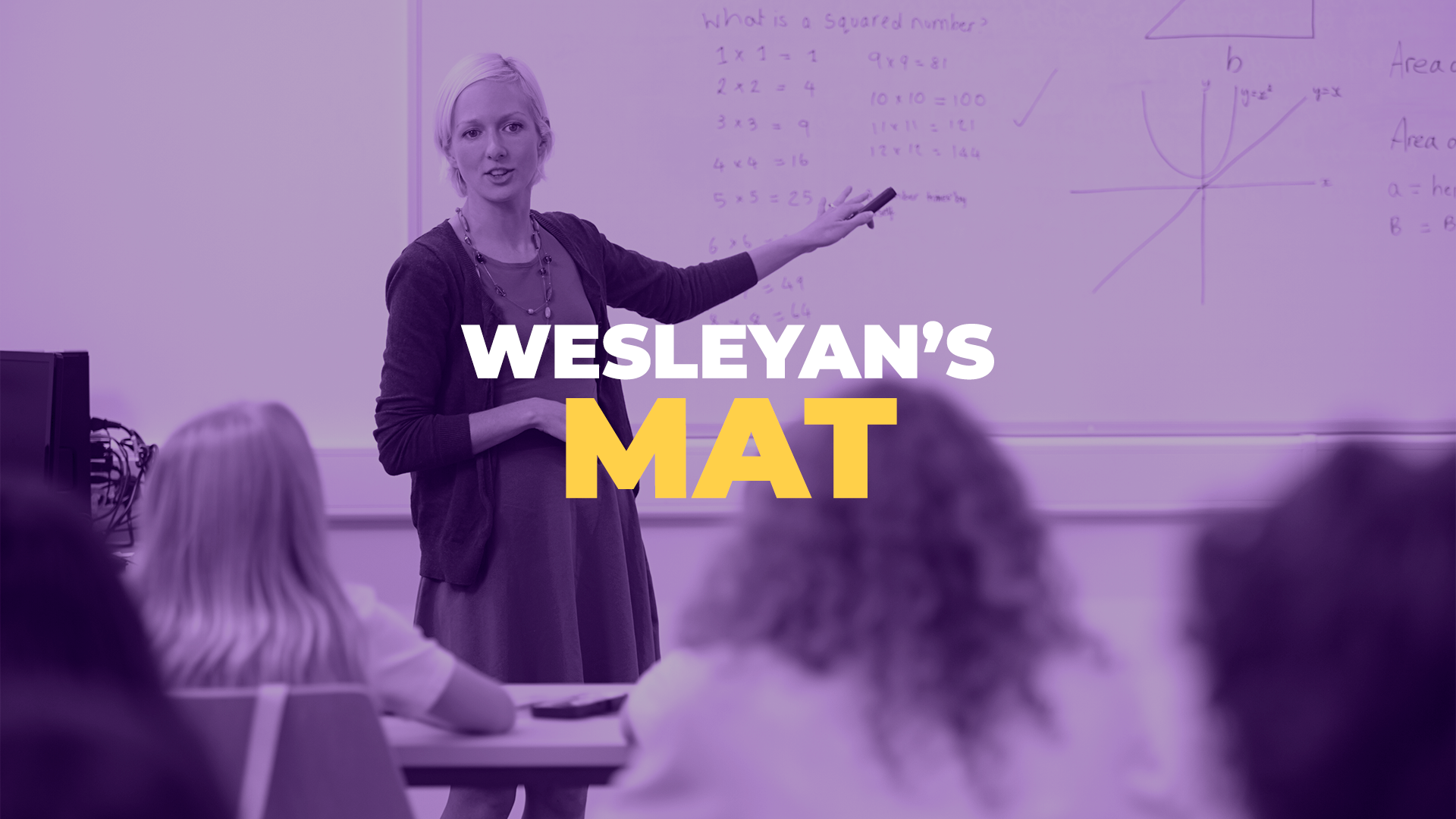A female teaching pointing to a whiteboard while teaching a class