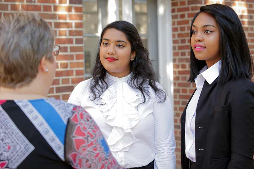 Two students dressed professionally on porch with employer.