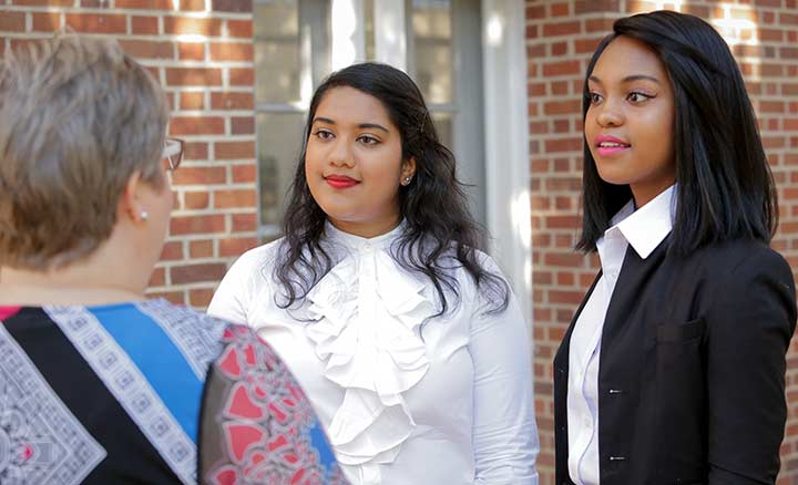 Two students dressed professionally on porch with employer.