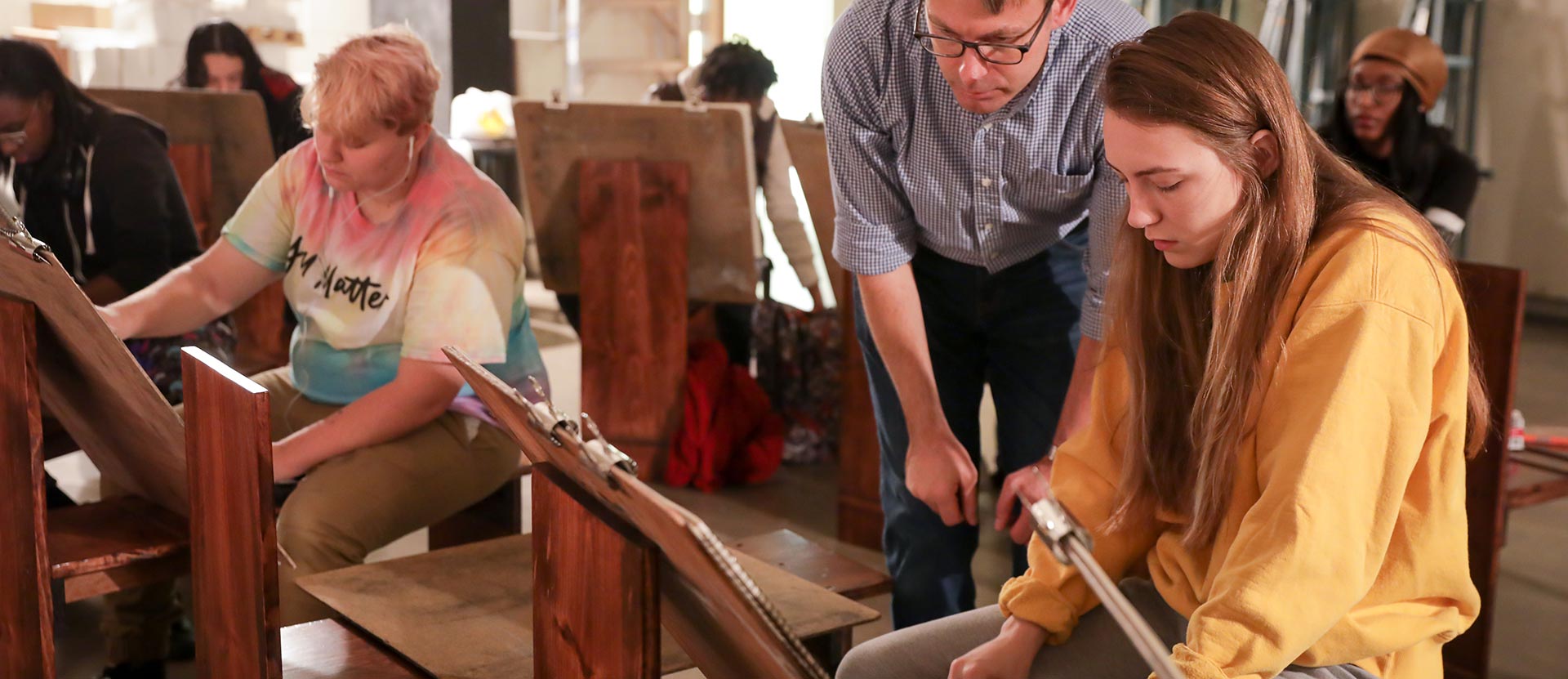 Two students and art professor in drawing class.