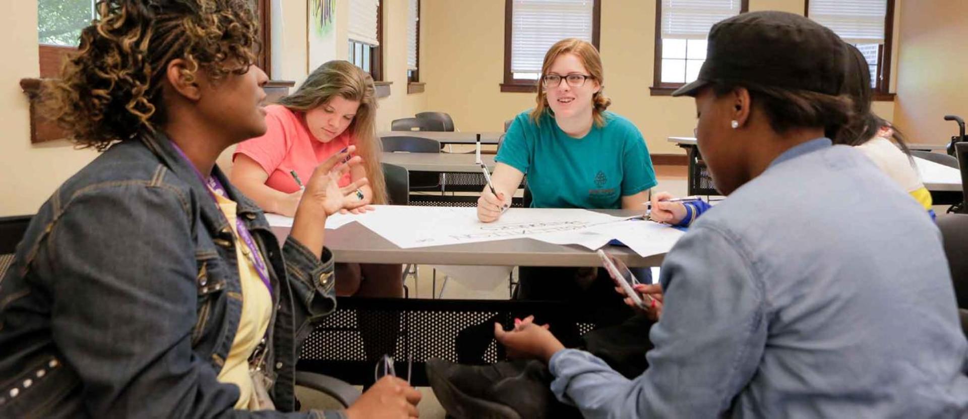 Students sit around table working on project in classroom