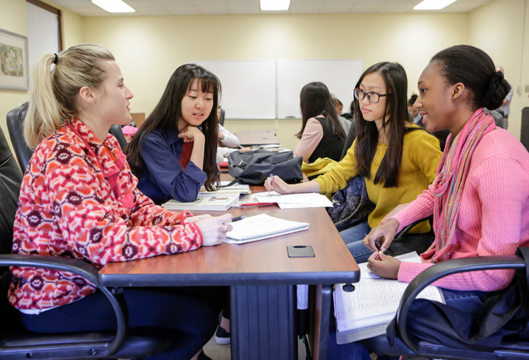 International Relations students work on project at table together.