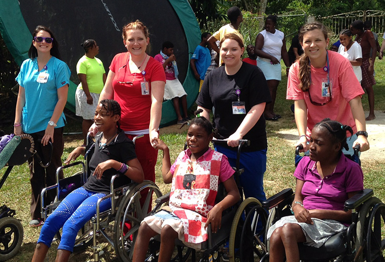 Nursing students on their Senior Mission helping roll kids in wheelchairs