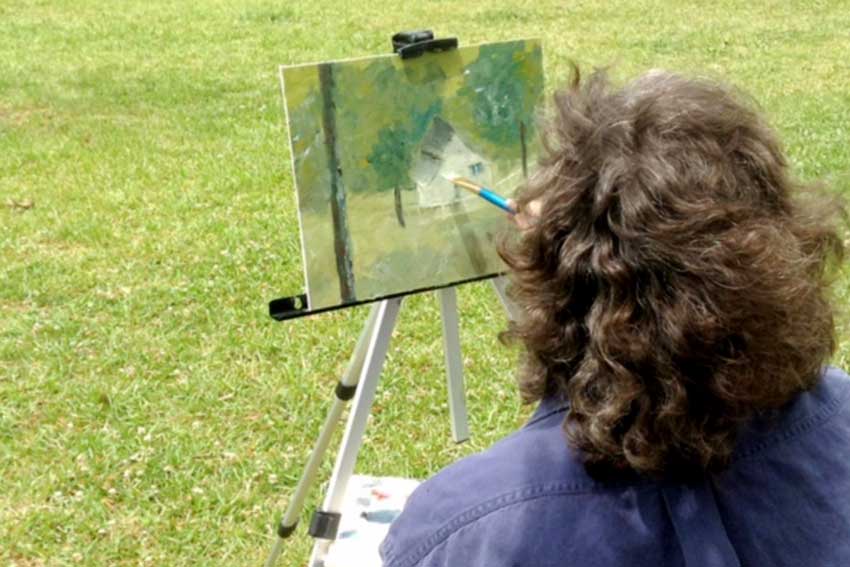 Woman painting a house outside.